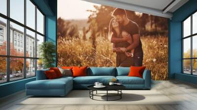 In the field illuminated by the sunlight. Beautiful young couple have a good time in the forest at daytime Wall mural