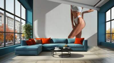 Indoors against the wall, beautiful sunlight. Young caucasian woman with slim body shape is indoors in the studio Wall mural