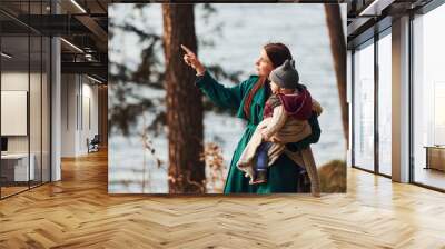 Mother with her little son have a walk in spring forest at daytime Wall mural