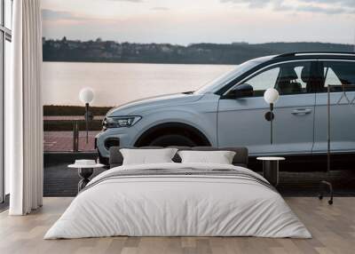 Particle side view of modern white car parked near lake at evening time Wall mural