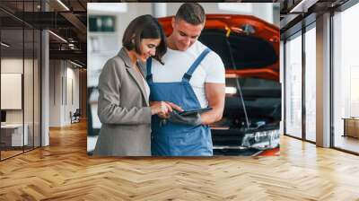 Paying for service. Man repairing woman's automobile indoors Wall mural