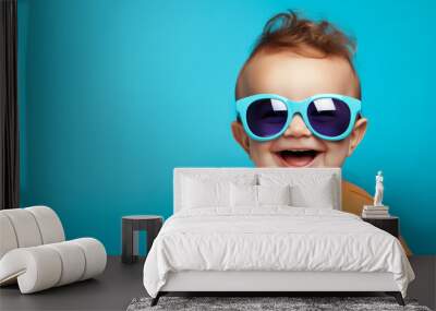 Portrait of happy positive funny baby wearing sunglasses. Against soft blue background Wall mural