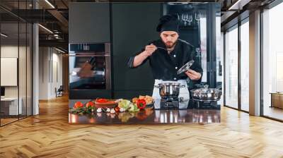 Professional young chef cook in uniform working on the kitchen Wall mural