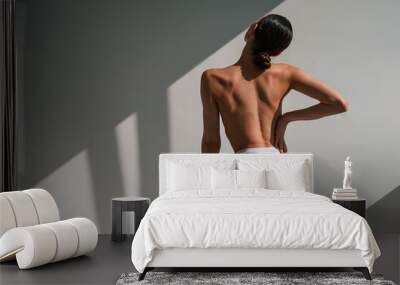 Rear view. Young caucasian woman with slim body shape is indoors in the studio Wall mural