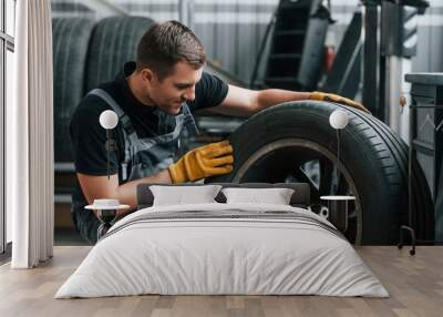 Replacement of the old tire. Man in uniform is working in the auto service Wall mural