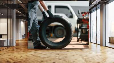 Rolling the wheel. Man is works in the automobile repairing salon Wall mural