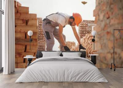 Side view, working and placing the bricks. Handsome Indian man is on the construction site Wall mural