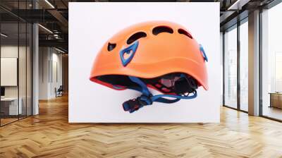 Side view. Isolated photo of climbing equipment - orange colored protective helmet Wall mural