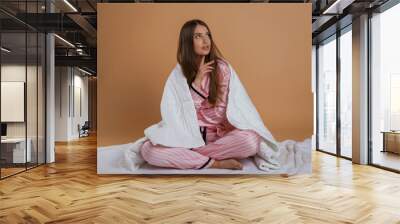 Sitting on the ground, in pajama, morning. Young pretty woman is against background in the studio Wall mural