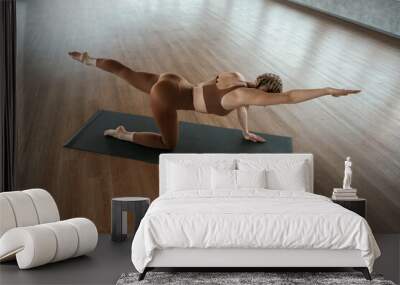 Spine exercise. Fitness woman in sportswear is indoors Wall mural