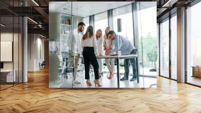 Standing by the table near big windows. Group of professional business people is in the office Wall mural