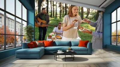 Tasty meal in hands. Group of friends are having picnic on the field with food in eco boxes Wall mural