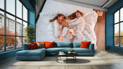 Tickling each other on the bed. Two little girls are playing and having fun together in domestic room Wall mural