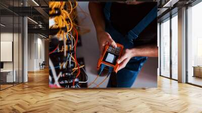 Top view of young man in uniform with measuring device that works with internet equipment and wires in server room Wall mural