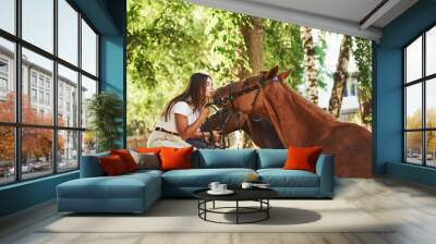 Two female horsewoman sitting on a fence near their pets on the farm Wall mural