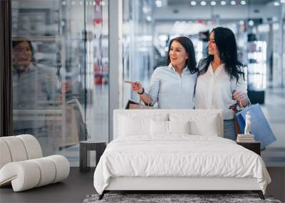 Two young women have a shopping day together in the supermarket Wall mural