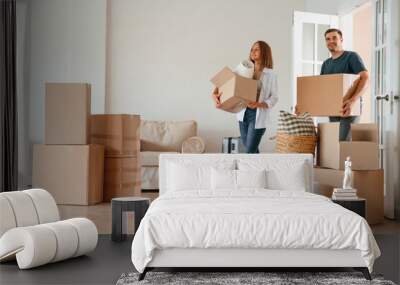 Walking forward with boxes. Young couple with dog are moving to new home Wall mural