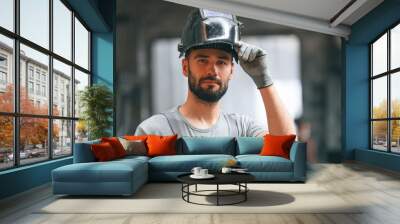 Welder man in safety helmet. Young factory worker in grey uniform Wall mural