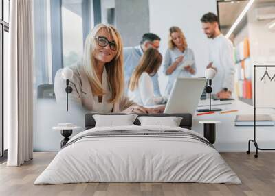 Woman working by using laptop. Group of professional business people is in the office Wall mural