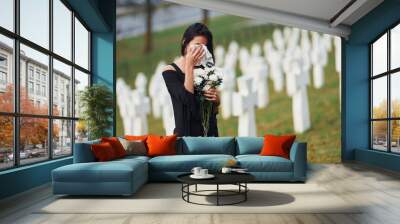 Young woman in black clothes visiting cemetery with many white crosses. Conception of funeral and death Wall mural