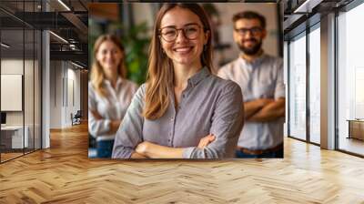 A woman with glasses and a smile, standing between two men in a modern office setting Wall mural