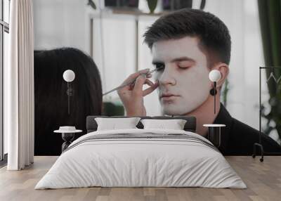 A young man is preparing makeup for Halloween. Create a Halloween look Wall mural