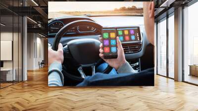 Car driver use smart phone with smart car app and use connection with car infotainment system while driving. Wall mural