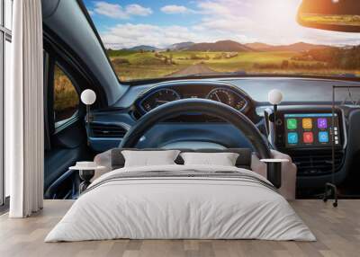 Driving car using the smart technologies that are displayed on board display. View from the driver's sight on the steering wheel, road and interior. Wall mural