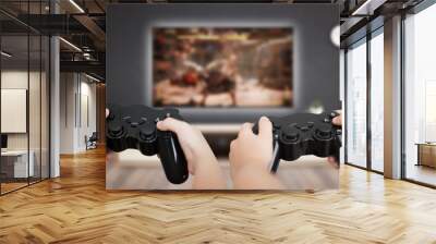 Gaming in living room concept. Two boys holding gamepad and play console game on TV. Wall mural