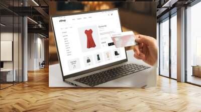 Shopping online with credit card concept. Modern e-commerce web page with woman clothes on laptop display Wall mural