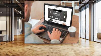 Web designer designs a modern flat website on a laptop. Coffee beside. Wall mural