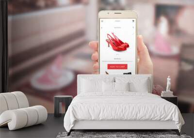 Woman showing modern gold smart phone with online shopping app on device display. Woman red shoes and add to cart button. Wall mural