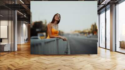 A young woman stands on a background of cityscape. Wall mural