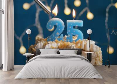 Birthday cake with 25 number candle on blue backgraund set on fire by lighter. Close-up Wall mural