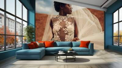 Black bride in wedding dress and bridal veil stands on background of beautiful landscape. Wall mural