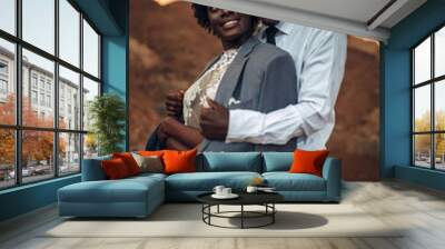 Groom hugs his bride dressed in his jacket in canyon at sunset. Wall mural