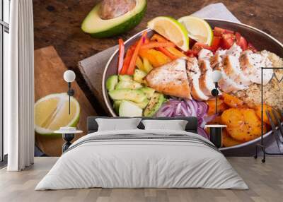 American delicious salad with chicken breast, vegetables, avacado, lettuce and quinoa in a plate on a wooden table Wall mural