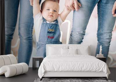 Parents lead and support by the hand their son making first steps. Wall mural