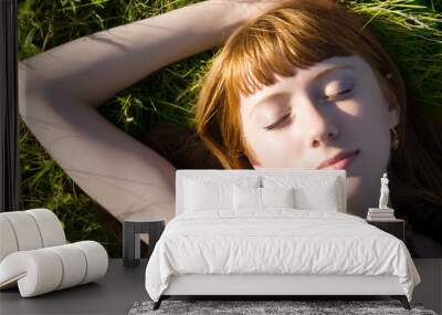 Young woman sleeping on a green grass Wall mural