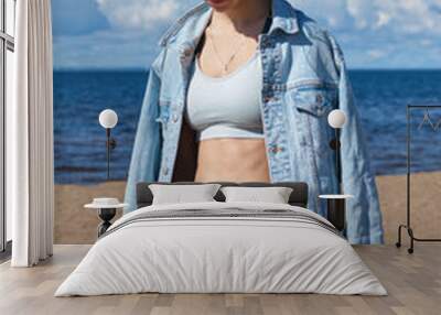 Young slim girl is engaged in a denim jacket on the beach Wall mural