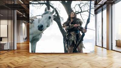 Woman in image of warrior amazon shoots a bow near her horse. Wall mural