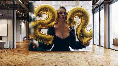 Young blonde woman celebrating her twenty two years birthday and holding figures of numbers 22. Wall mural