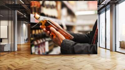 A man takes alcoholic drinks from the supermarket shelf. Shopping for alcohol in the store. Wall mural