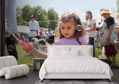 Little girl plays with soap bubbles at a holiday Wall mural