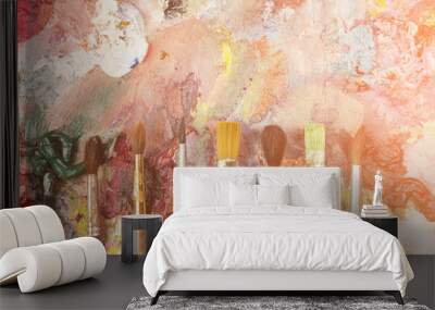 Paintbrushes closeup, artist palette and multicolor paint stains. Toned Wall mural