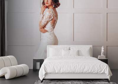 Young beautiful bride in a lace wedding dress in the studio on a white background Wall mural