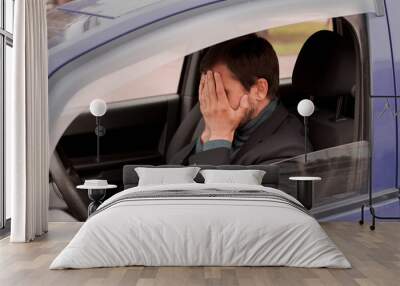 Young man sitting inside car is very upset and stressed Wall mural