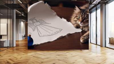 beautiful tabby cat looking at hand made drawing - sketch of angel with blue christmas ball, xmas and pets concept  Wall mural