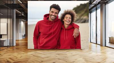 A couple in red hoodies standing on the beach. AI Wall mural