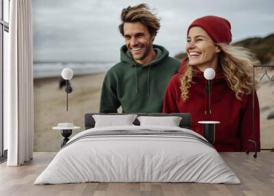 A man and woman wearing red and green hoodies on the beach. AI Wall mural